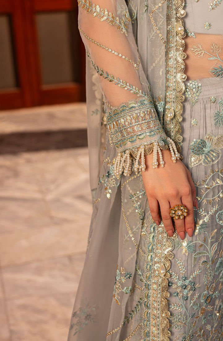 Close-up of a person wearing a aqua embroidered outfit with jewelry on a blurred background