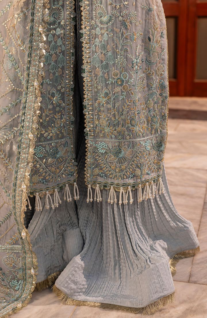 Decorative fabric with intricate patterns and tassels on a wooden floor.