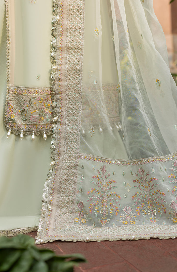 Close-up of a light green embroidered fabric with floral patterns on a red surface.